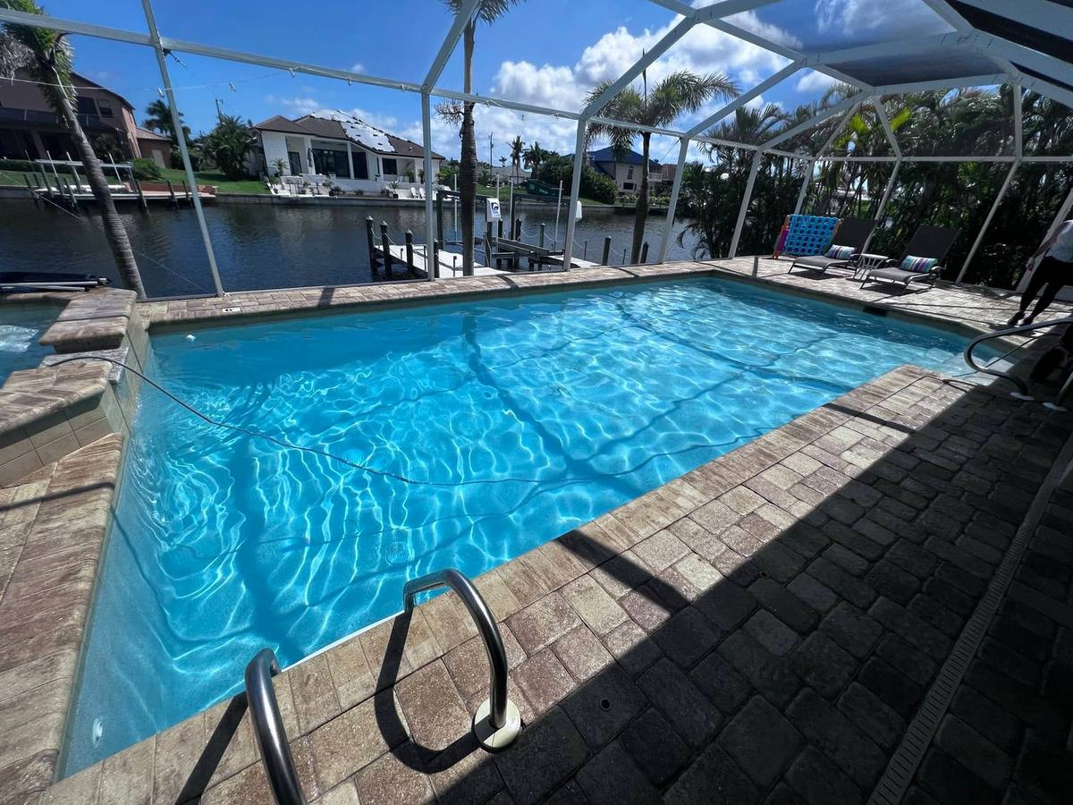 Sealed paver pool deck on a canal-front home with a boat dock in the background