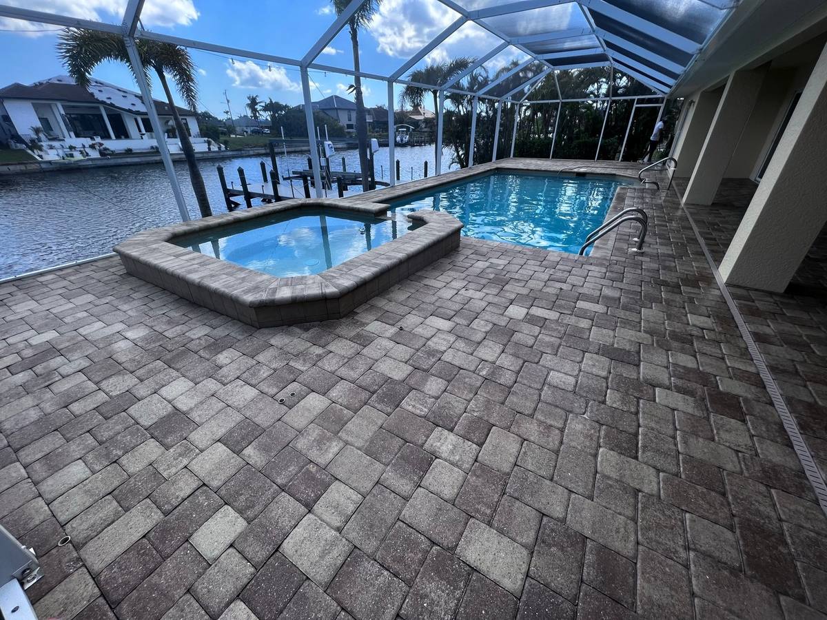Cleaned and sealed paver pool deck in a screened lanai on a canal