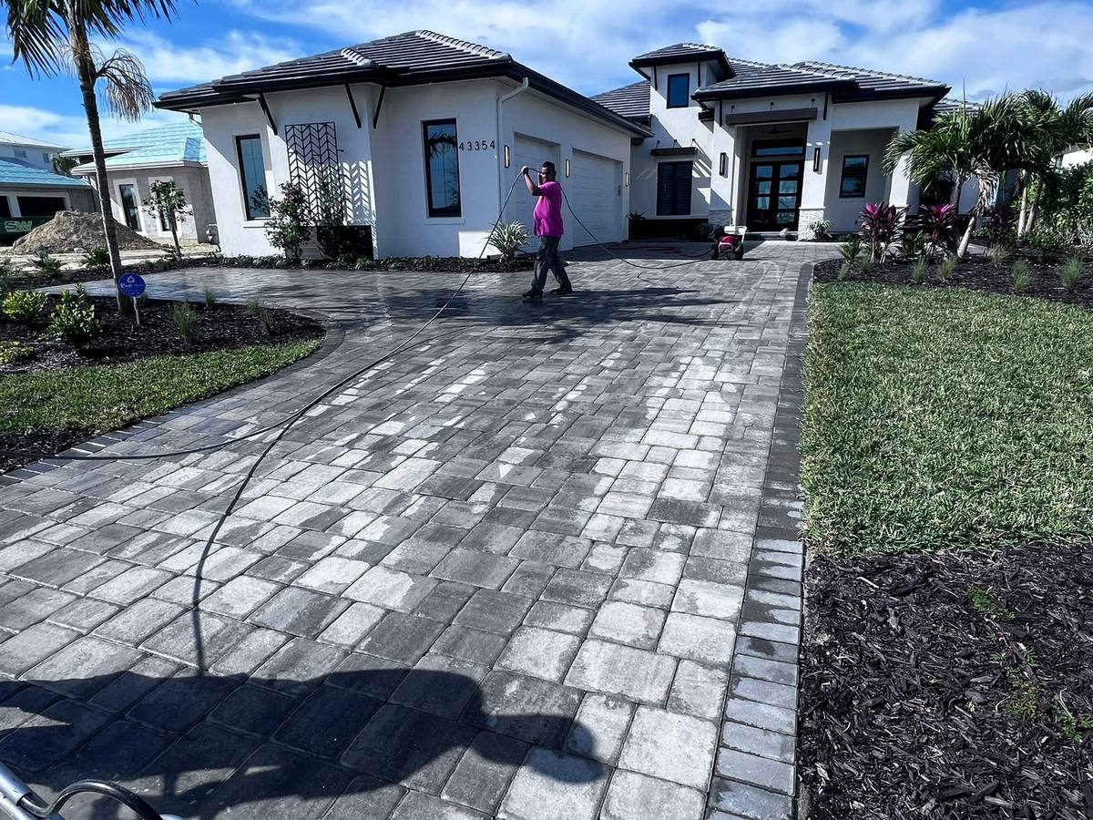 Paver Savers crew member pressure washing a paver driveway in front of a new Babcock Ranch home