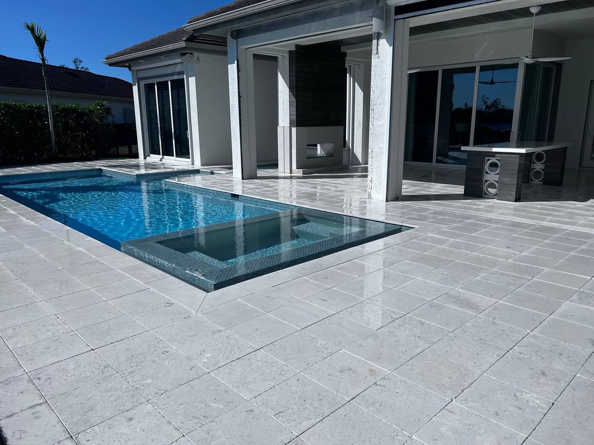 Bright, sealed paver pool deck at a modern Estero home