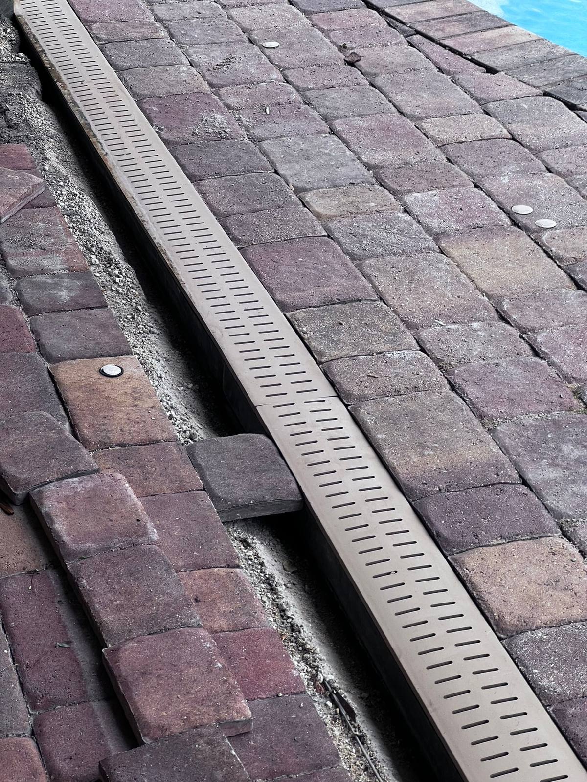 Trench drain installed neatly between red pavers
