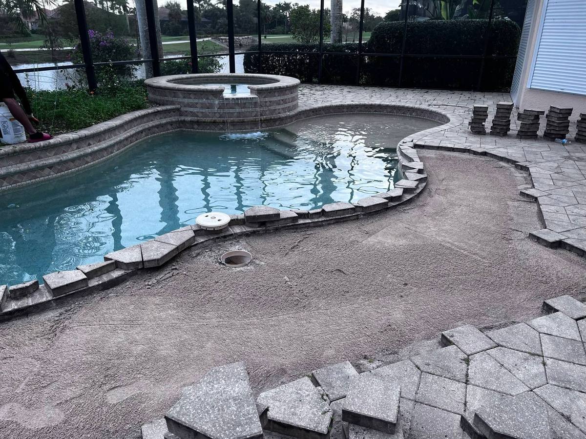 Pool deck pavers lifted and the base re-leveled during a paver repair around a spa and pool