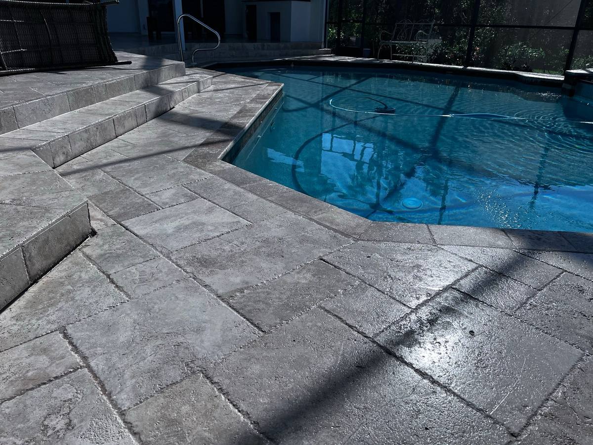 Sealed travertine pool deck with a screened pool cage